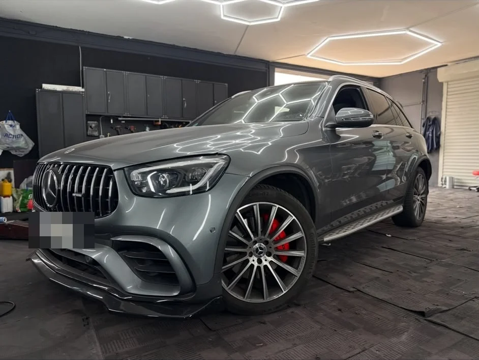 Grauer Mercedes-AMG SUV mit roten Bremssätteln, die Deckenleuchten laufen als klare Linien über Haube und Flanke